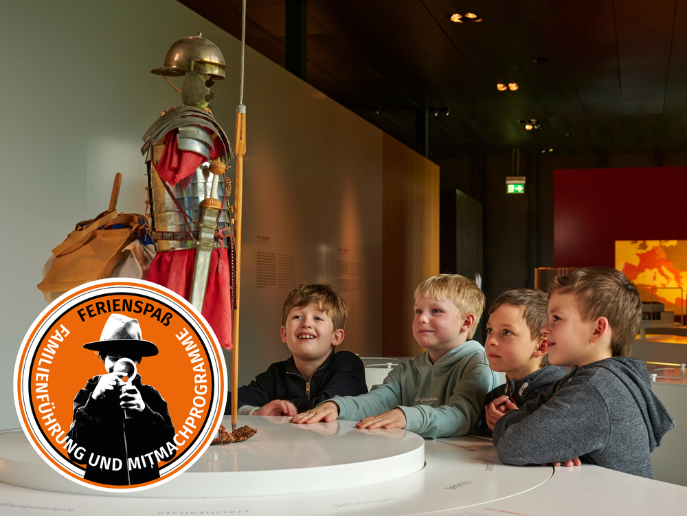 Vier Kinder schauen sich die Rüstung eines Römers im Modell an.